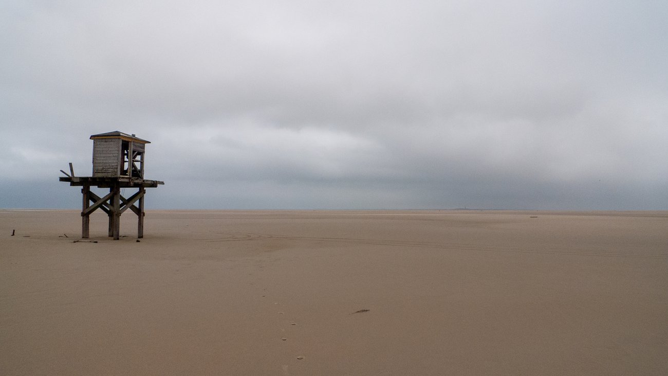 Flat beach with ruined lifeguard tower on Vlieland island